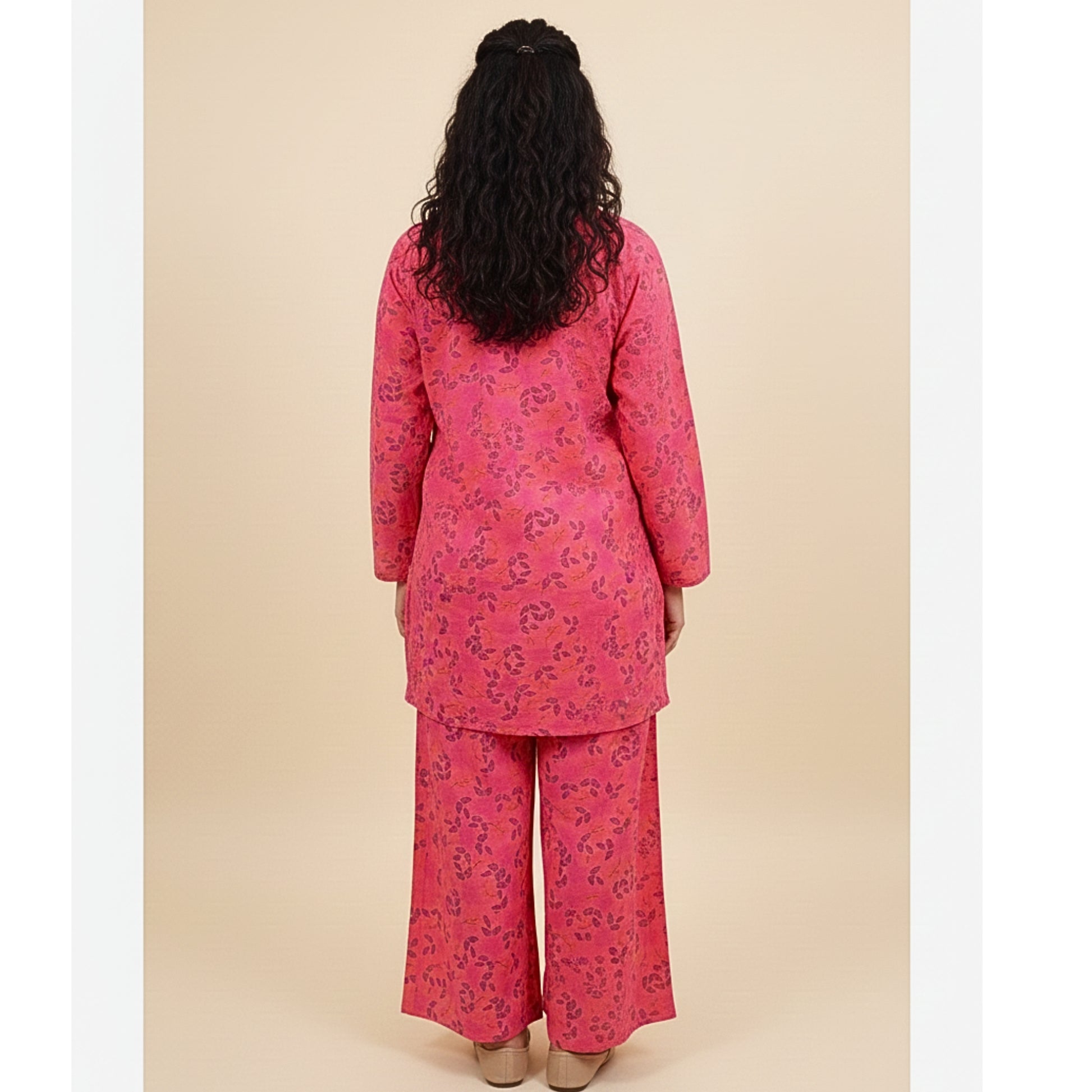 Woman wearing a pink floral outfit against a beige background