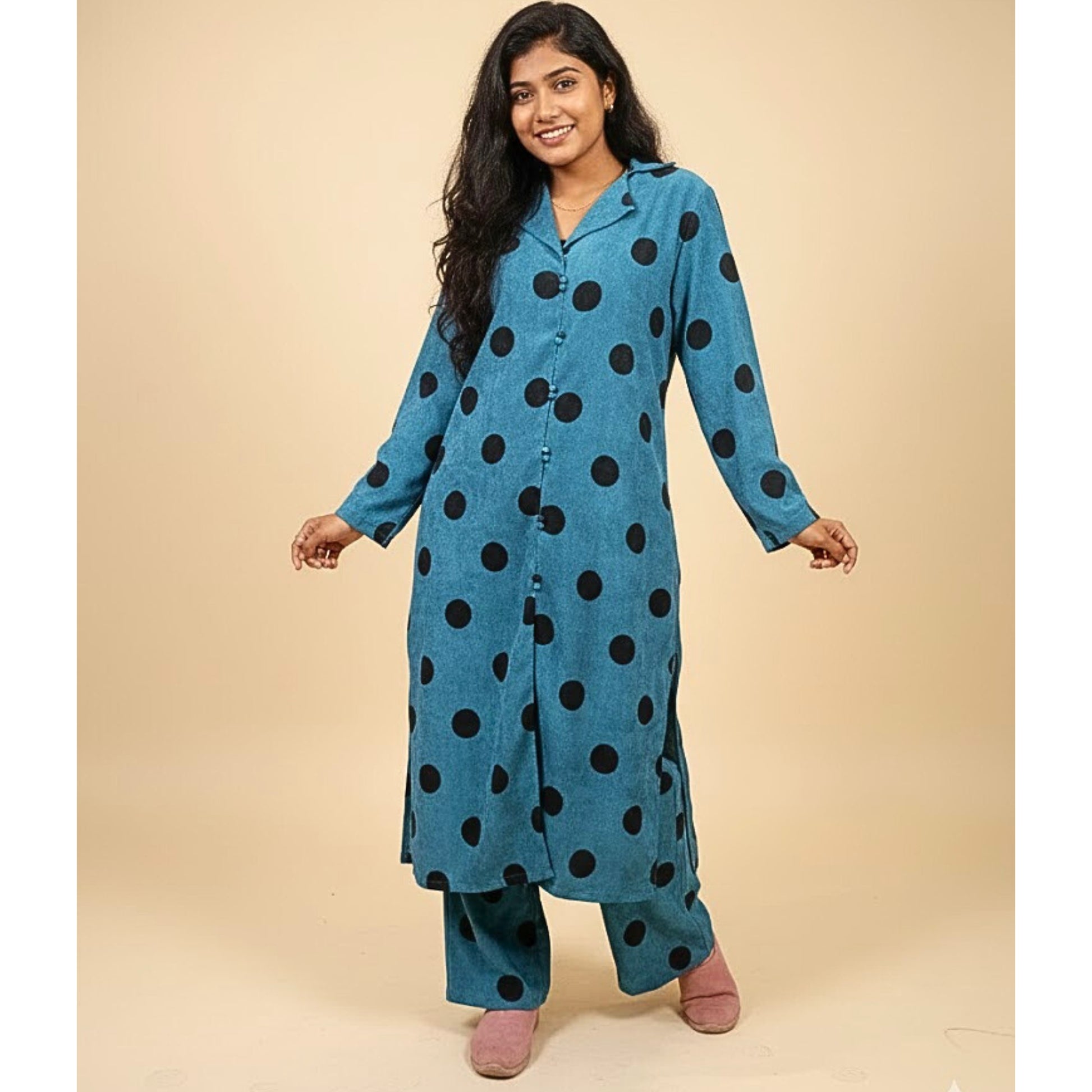 Woman wearing a blue polka dot kurta with pink shoes on a beige background