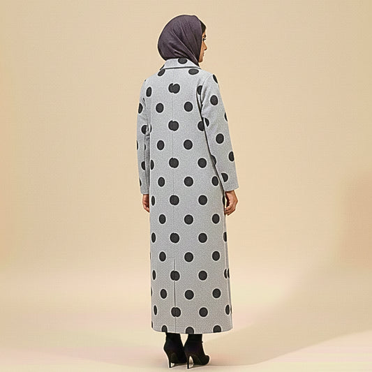 Person wearing a long polka dot coat on a beige background