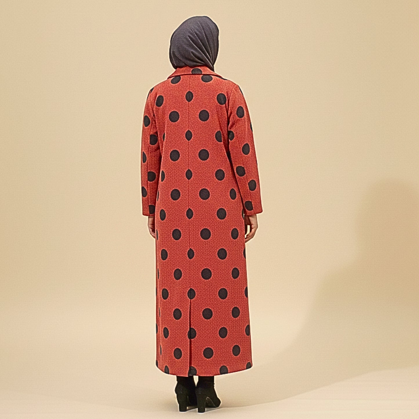 Person wearing a red coat with black polka dots on a beige background