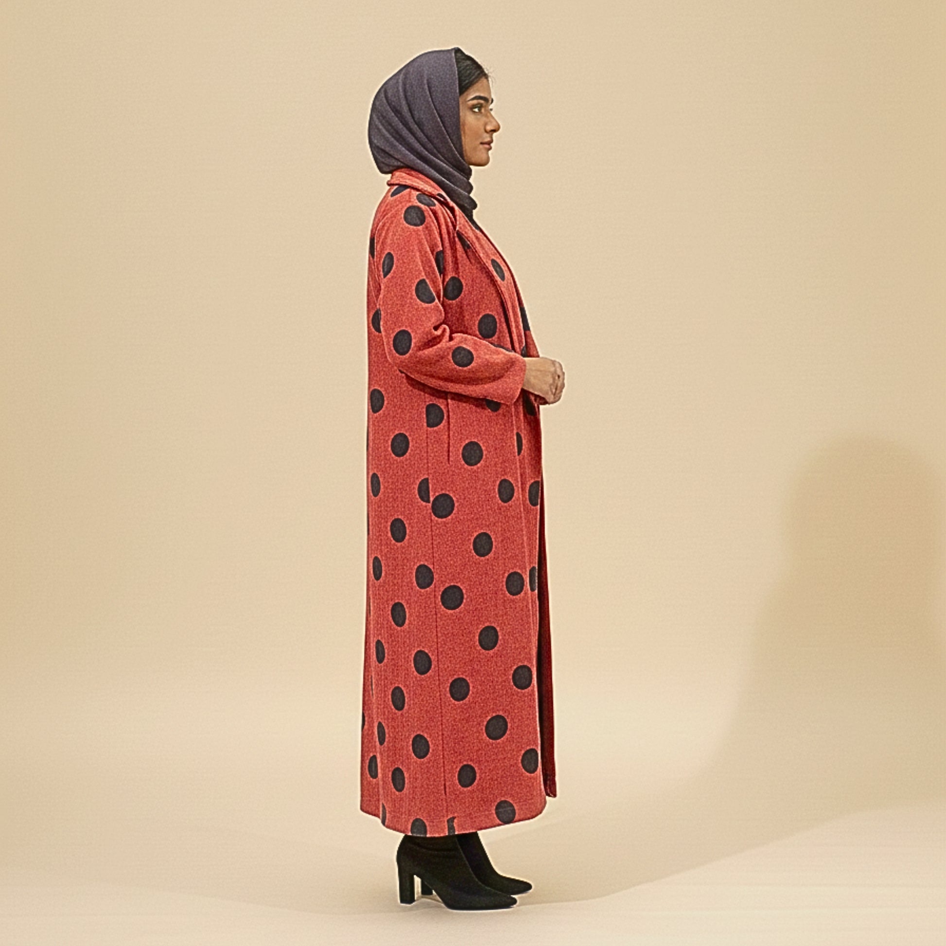 Woman wearing a red coat with black polka dots on a beige background