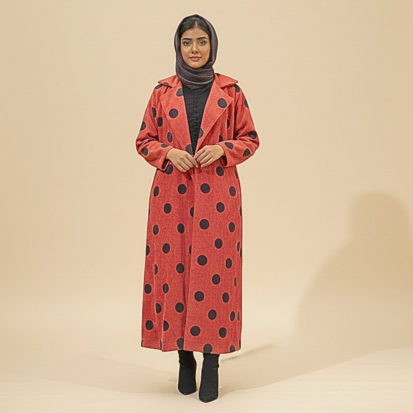 Woman wearing a red coat with black polka dots on a beige background